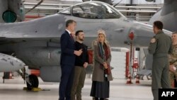 Президент України Володимир Зеленський (в середині) з бельгійським прем’єр-міністром Александром Де Кроо (ліворуч) з міністеркою оборони Бельгії Людивін Дедондер біля літака F-16. 30 таких літаків Бельгія зобов’язалася надати Україні.