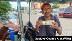 ARCHIVVO - Un vendedor ambulante de golosinas y cigarros muestra un billete de un dólar estadounidense en Maracaibo, Venezuela, en agosto de 2023.