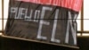 ARCHIVO - Un agente colombiano quita una bandera del Ejército de Liberación Nacional con explosivos ocultos en un puente en Medellín, en julio de 2004.