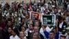 Manifestantes sostienen flores y carteles durante un evento para recordar a los exguerrilleros y líderes sociales asesinados después de la firma de un acuerdo de paz en 2016, en Bogotá, Colombia, el martes 20 de febrero de 2024. 