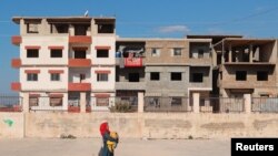 FILE - A woman walks by a school in Jableh, Syria, Feb. 16, 2023. Though Syrian schools resumed classes Feb. 25, 2023, many students were absent from class because their homes were destroyed in a Feb. 6, 2023 earthquake, forcing them to find shelter far from their schools.