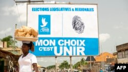 Une femme passe devant une affiche de campagne du parti au pouvoir Union pour la République (UNIR), à Lomé, le 24 avril 2024. 