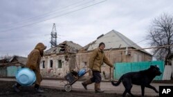 Hennadiy Mazepa y su esposa, Natalia Ishkova, caminan mientras recolectan madera de casas destruidas por bombardeos rusos en Chasiv Yar, Ucrania, 3 de marzo de 2023