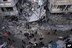 Palestinians inspect the damage to residential buildings after an Israeli airstrike in Rafah, southern Gaza Strip, March 24, 2024.