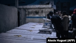 Les proches des personnes tuées fin août par l'armée à Goma regardent l'intérieur des cercueils alors qu'ils sont déchargés dans un cimetière.