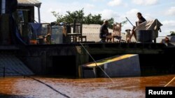 ARCHIVO - Hombres sentados en el techo de una casa en una zona inundada en Canoas, estado de Rio Grande do Sul, Brasil, 14 de mayo de 2024.