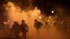 FILE - French CRS riot police run amid clashes with protesters during a demonstration as part of the ninth day of nationwide strikes and protests against French government's pension reform, in Paris, March 23, 2023. 