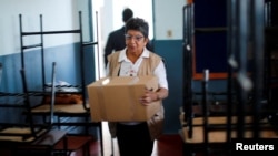 Una funcionaria del Tribunal Superior de Justicia Electoral de Paraguay traslada una caja que contiene una máquina de votación a una escuela pública, que será un centro de votación, un día antes de las elecciones presidenciales, en Asunción, Paraguay, 29 de abril de 2023. REUTERS/Agustin Marcarian