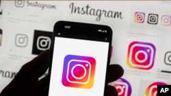 FILE - The Instagram logo is seen on a cell phone, Oct. 14, 2022, in Boston. Google, Facebook, TikTok and other Big Tech companies operating in Europe are facing far-reaching efforts to clean up what people encounter online. 