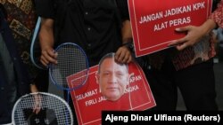 Para pengunjuk rasa membawa raket badminton, poster dan topeng bergambar wajah Ketua KPK Firli Bahuri saat demo di depan gedung KPK di Jakarta, 23 November 2023. (Foto: Ajeng Dinar Ulfiana/Reuters)