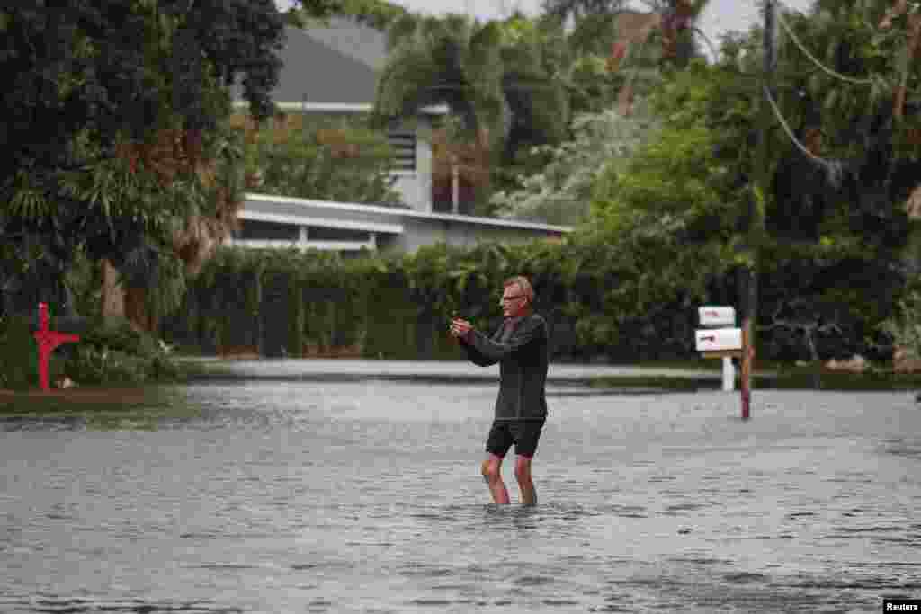 Víctor Cristia camina con el agua debajo de sus rodillas en medio de la inundación a causa del huracán Idalia, mientras fotografía su residencia en Clearwater Beach.