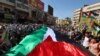 Orang-orang di Kota Nablus, di Tepi Barat yang diduduki, membentangkan bendera Palestina raksasa dalam pawai untuk menunjukkan dukungan terhadap warga di Jalur Gaza di tengah pertempuran antara Israel dan Hamas, Kamis, 26 Oktober 2023. (Foto: Zain Jaafar/AFP)