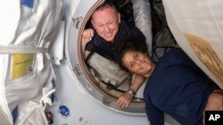 In this photo provided by NASA, Boeing Crew Flight Test astronauts Butch Wilmore, left, and Suni Williams pose for a portrait inside the vestibule between the forward port on the ISS's Harmony module and Boeing's Starliner spacecraft on June 13, 2024.