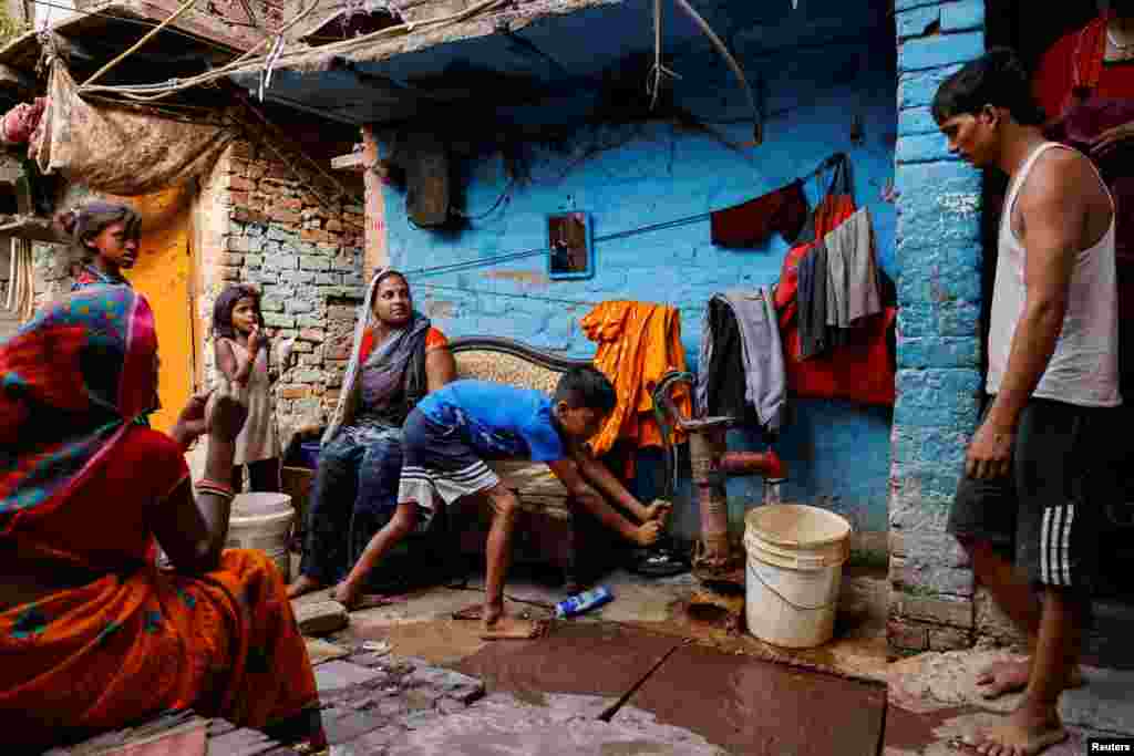A boy fills water in a container using a hand pump on a hot summer day during a heatwave in New Delhi, India.