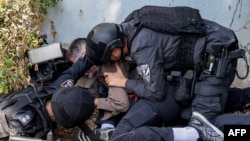 Policajac i pripadnik specijalnih snaga pomažu novinaru da se zaštiti tokom raketnog napada u Sderotu kod Gaze. 12. oktobar 2023. 