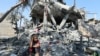 Un enfant est assis au milieu des décombres alors que les Palestiniens inspectent une maison détruite par une frappe israélienne, dans le cadre du conflit entre Israël et le Hamas, dans le camp de réfugiés de Nusairat, dans le centre de la bande de Gaza, le 9 juillet 2024.
