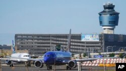 FILE - LaGuardia Airport's air traffic control tower, right, is shown as planes line up for take-off, May 25, 2023, in New York.