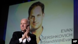 El presidente Joe Biden se para con la audiencia y aplaude mientras una imagen del periodista Evan Gershkovich aparece en la pantalla durante la cena de la Asociación de Corresponsales de la Casa Blanca en el Washington Hilton en Washington, el 29 de abril de 2023.