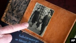 Holocaust survivor Herbert Rubinstein shows pictures of him with his parents during an interview with The Associated Press at his home in Duesseldorf, Germany, April 25, 2024.