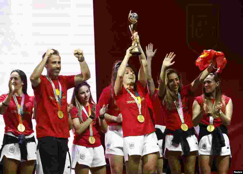 El seleccionador español, Jorge Vilda, y las jugadoras Ivana Andrés, con el trofeo, y Olga Carmona, la gran estrella de la final tras marcar el tanto de la victoria frente a Inglaterra y que supo de la muerte de su padre tras el encuentro, con una camiseta en sus manos, celebran el título con los miles de aficionados que se dieron cita en la explanada Puente del Rey, en Madrid.