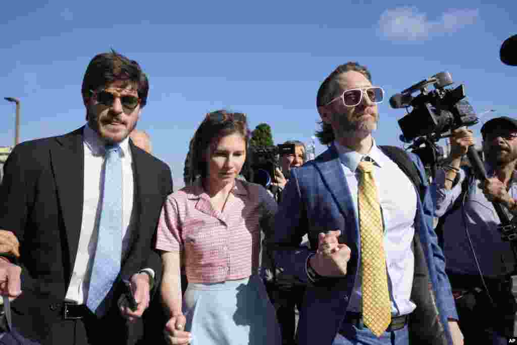 Amanda Knox arrives flanked by her husband Christopher Robinson, right, and her layer Luca Luparia Donati at the Florence courtroom in Florence. Amanda Knox returns to an Italian courtroom for the first time in more than 12½ years to clear herself "once and for all" of a slander charge that stuck even after she was exonerated in the brutal 2007 murder of her British roommate in the idyllic hilltop town of Perugia.