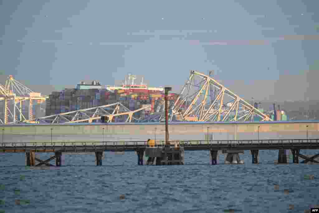 The steel frame of the Francis Scott Key Bridge sits on top of a container ship after it struck the bridge in Baltimore, March 26, 2024. The collapse sent multiple vehicles and up to 20 people plunging into the harbor below. 