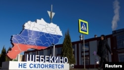 FILE - A woman walks past an installation that displays the map of the Belgorod region and the slogan “Shebekino does not bow down,” in the town of Shebekino, Russia, March 11, 2024.
