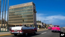 FILE - Tourists in classic cars pass the U.S. Embassy in Havana, Cuba, Oct. 3, 2017. Brain injuries known as the “Havana Syndrome” were first reported by some American diplomats who were posted in Cuba.