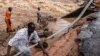 FILE - Men gather to asses the damage in the section of a road collapsing due to flash floods at the Mwingi-Garissa Road near Garissa, Kenya, on Nov. 22, 2023. 