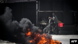 Warga Palestina melihat dari balik ban yang terbakar saat serangan Israel di kota Jenin di Tepi Barat yang diduduki, 21 Mei 2024.