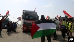 Volonte flote drapo Palestinyen ak Ejipsyen pou akeyi yon kamyon kap transpote asistans imanite nan Gaza, nan moman lap travese fwontye Rafah a, nan Rafah, Ejipt, Dimanch 22 Oktob, 2023.