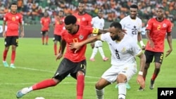 Mexer luta pela bola com o avançado do Gana, Jordan Ayew, autor dos dois golos da sua equipa, durante o jogo do grupo B do CAN 2023 entre Moçambique e Gana, no Estádio Olímpico Alassane Ouattara em Ebimpe, Abidjan, 22 janeiro 2024. (Issouf SANOGO/AFP)