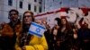 Seorang peserta aksi memegang bendera Israel dalam aksi mengenang korban serangan kelompok militan Hamas, yang digelar oleh Komunitas Yahudi di Wina, Austria, pada 11 Oktober 2023. (Foto: AFP/Joe Klamar)
