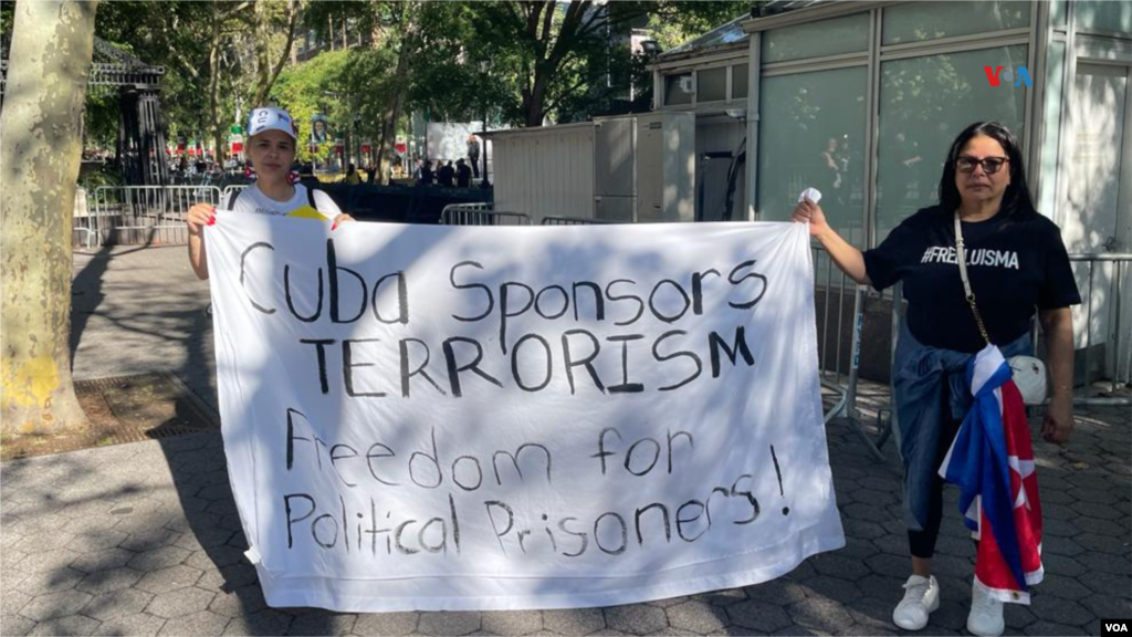 Exiliados cubanos sostienen un cartel donde se lee en inglés "Cuba, patrocinadores del terrorismo. Libertad para los presos políticos", en una plaza en las afueras de la sede de la ONU en Nueva York, el 19 de septiembre de 2023.