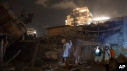 FILE - People inspect the damage from a rocket fired from the Gaza Strip, in Tel Aviv, Israel, Oct. 7, 2023.