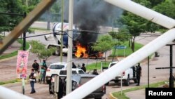 Pistoleros del cartel se ven cerca de un camión en llamas durante los enfrentamientos con las fuerzas federales tras la detención de Ovidio Guzmán, hijo de "El Chapo" Guzmán, y hermano de Joaquín Guzmán López, en Culiacán, estado de Sinaloa, México, el 17 de octubre de 2019.