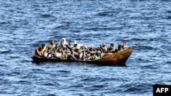 FILE - Migrants of African origin are crammed on board of a small boat as Tunisian coast guards prepare to transfer them onto their vessel, at sea between Tunisia and Italy, Aug. 10, 2023. 