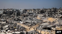 ARCHIVO - Personas caminan entre los escombros de edificios destruidos en Khan Yunis, Franja de Gaza, el 16 de abril de 2024. Es probable que los escombros de Gaza estén mezclados con municiones sin explotar, dicen expertos de la ONU en minas terrestres y explosivos.