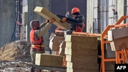 FILE - Laborers work on a construction site in Moscow, March 12, 2021. Thousands of Uzbeks working in Russia now are considering returning home to help with the construction of the "New Tashkent" development projects.