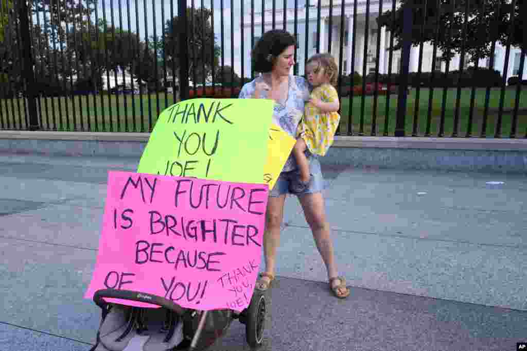 Anna Filipic sostiene a su hija Louisa, junto a pancartas en apoyo al presidente Biden en su decisión de dejar la carrera por la reelección. En las cartulinas se lee en inglés: "Gracias Joe. Mi futuro es más brillante debido a ti". 