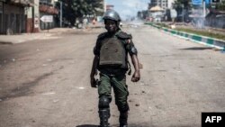 Dans les rues de Conakry, des hommes armés et casqués dispersent tout attroupement et ordonnent à la population de rentrer chez elle.