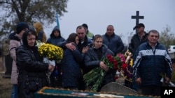 Familiares y amigos lloran cerca de los ataúdes de Tatiana Androsovych, de 60 años, y Mykola Androsovych, de 63, muertos por un ataque con cohete, en un cementerio en la aldea de Hroza, cerca de Kharkiv, Ucrania, el 7 de octubre de 2023.