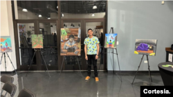 Yeison Pérez posando junto a su exhibición que muestra la ruta
migratoria que recorrió.