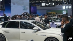 FILE - Visitors look at cars at the BYD booth during the China Auto Show in Beijing, China, Apr. 26, 2024. The EU threatened, June 12, 2024, to hike tariffs on Chinese electric vehicles, escalating a trade dispute over Beijing's subsidies for the exports.
