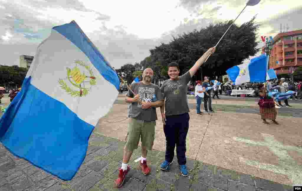 El guatemalteco Aldo Bocaletti ondea una bandera de Guatemala y comenta a la Voz de América que es necesario hacer algo para tener un mejor futuro para las nuevas generaciones. Manifestación en la Plaza de la Constitución, en Ciudad de Guatemala, el 13 de octubre de 2023. Foto: Eugenia Sagastume, VOA.