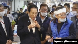 기시다 후미오(가운데) 일본 총리가 지난 8월 도쿄 시내 수산물 시장에서 후쿠시마산 수산물을 시식하고 있다. (자료사진)