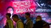 Para pendukung Gibran Rakabuming Raka, putra sulung Presiden Joko Widodo, berjalan di depan poster di Jakarta ajakan untuk mendukung pencalonan Gibran sebagai bakal calon wakil presiden dalam pemilihan presiden 2024, Sabtu, 21 Oktober 2023. (Foto: Bay Ismoyo/AFP)