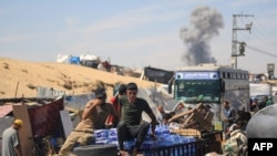 Asap tampak mengepul di latar belakang menyusul pemboman Israel, sementara warga Palestina berusaha mengungsi meninggalkan kota Rafah di Jalur Gaza selatan, hari Jumat 31 Mei 2024.
