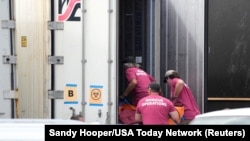 ARCHIVO: Trabajadores de una morgue colocan cadáveres en bolsas en un camión refrigerado en una instalación forense de Maui, Hawái, el 15 de agosto de 2023.