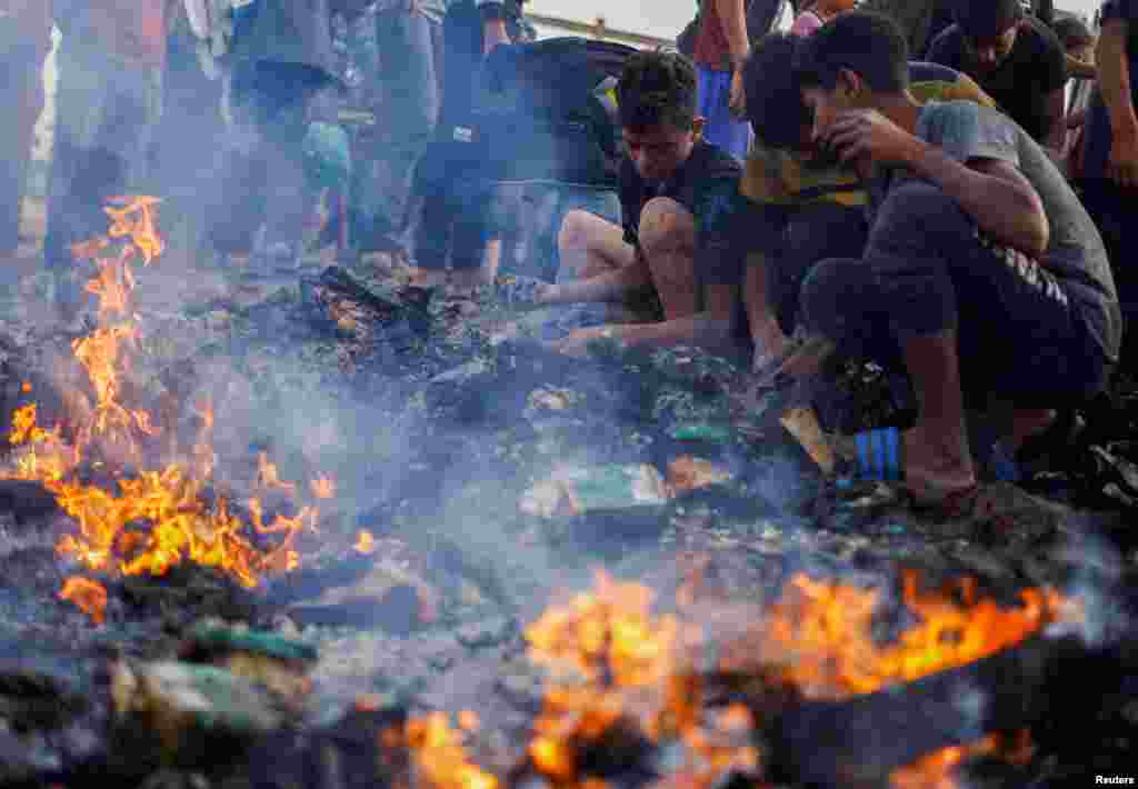 Palestinians search for food among burnt debris in the aftermath of an Israeli strike on an area designated for displaced people, in Rafah in the southern Gaza Strip.